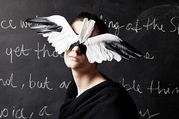 photo of a woman dressed in black sitting in front of a chalkboard