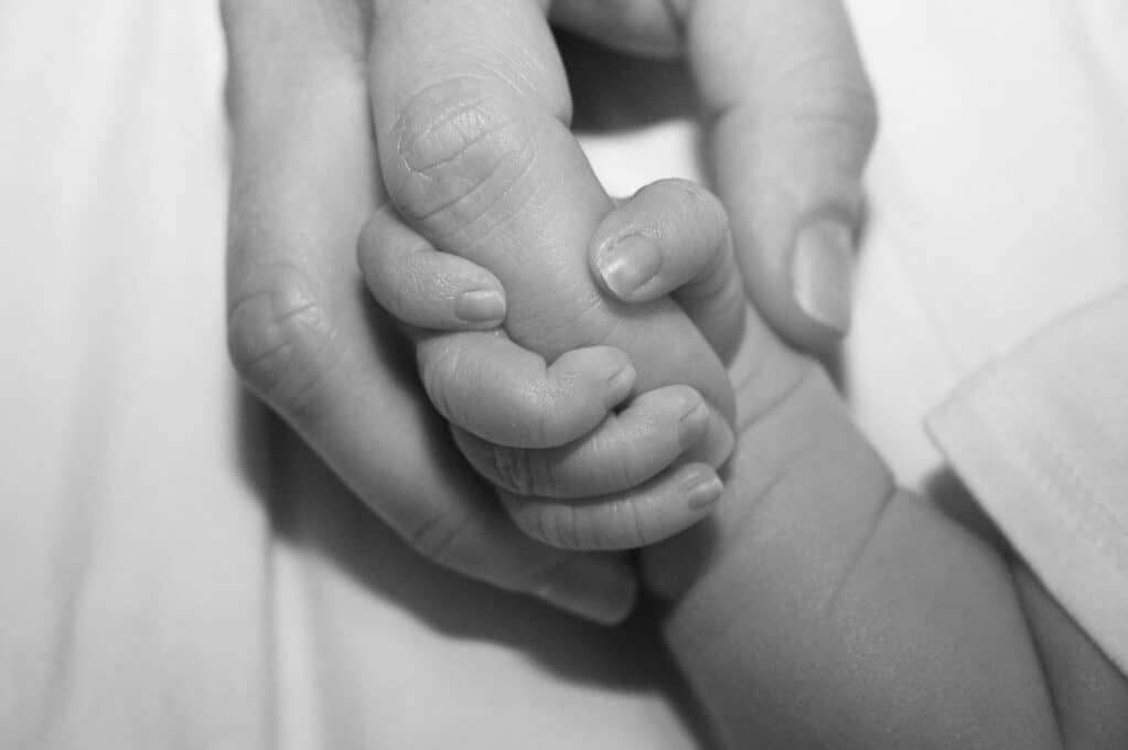 photo of a baby's hand holding an adult finger