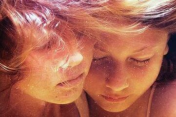 photo of two children hugging underwater