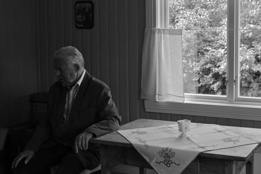 photo of old man sitting next to table