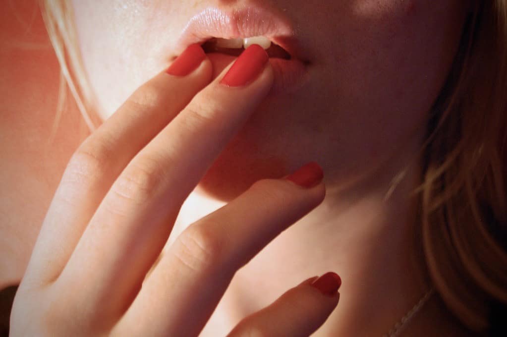 photo of woman's fingers touching her lips