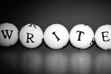 Black & white image of letters on 5 small balls that spell out the word "writer"