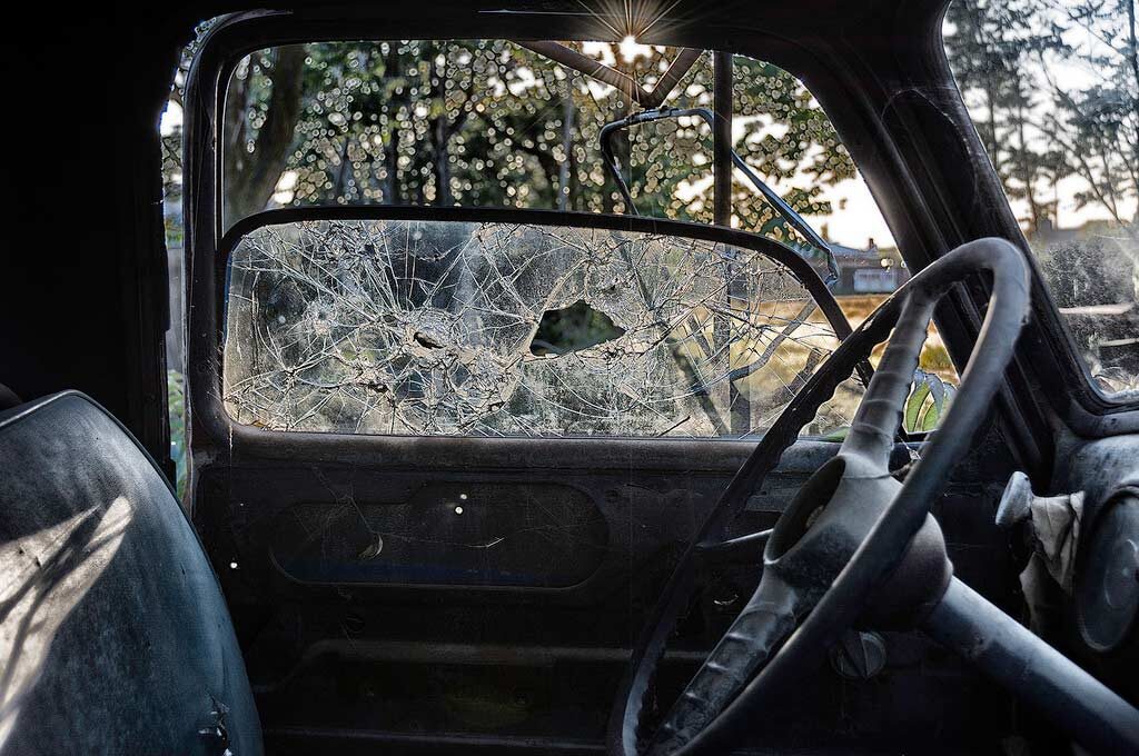 photo from inside of vehicle with a broken window next to steering wheel