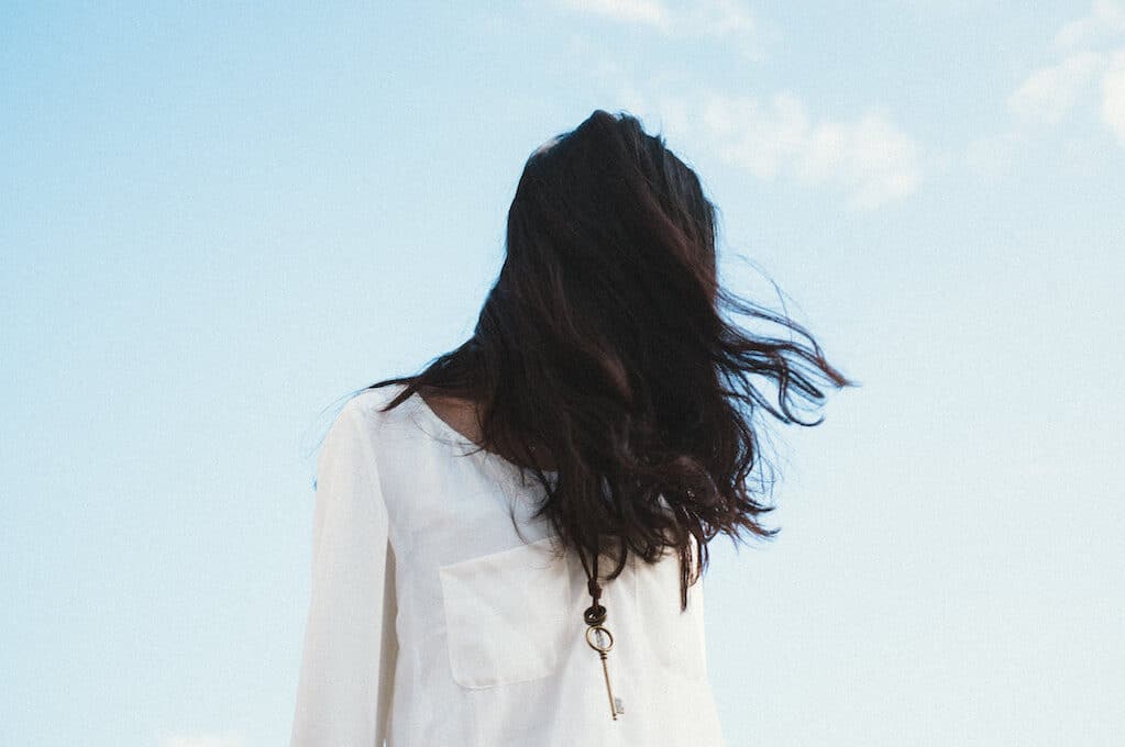 photo of girl with dark hair covering her face