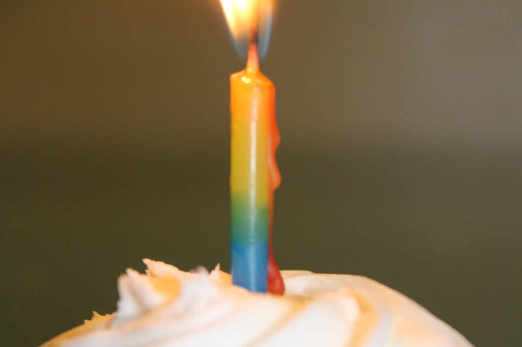 photo of chocolate cupcake with white icing and lit candle on top