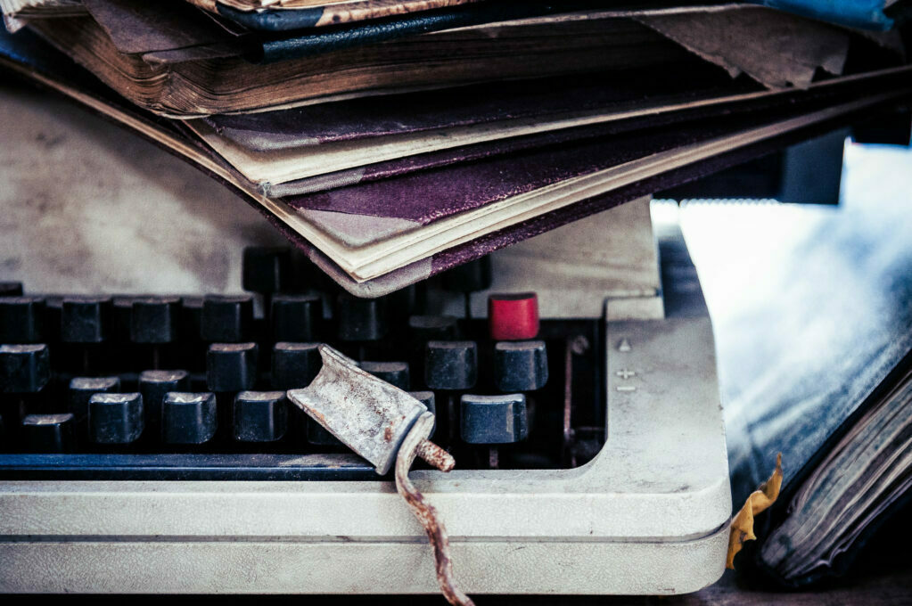 photo of typewriter with notebooks piled on top