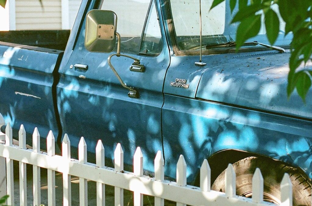 photo of old pickup truck next to fence