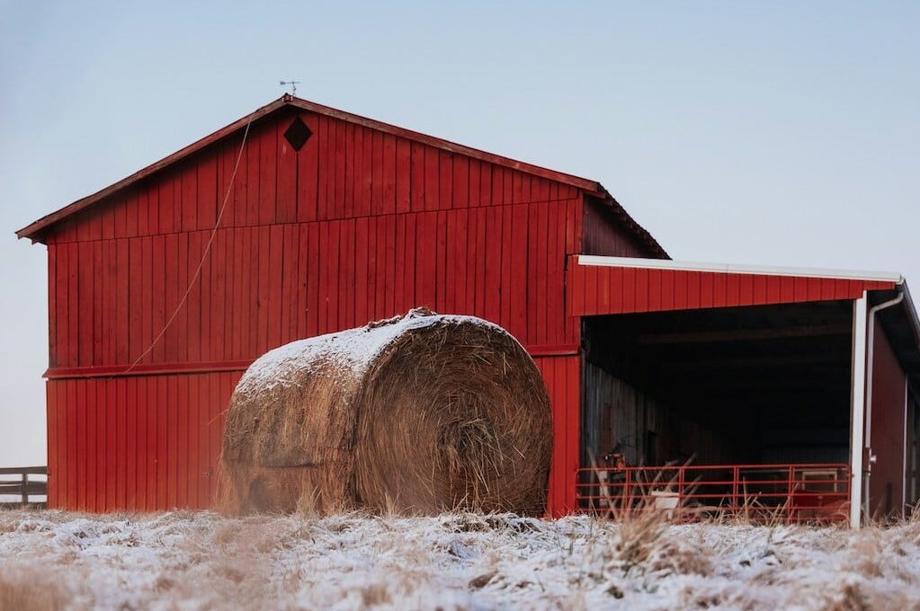 red barn with hay bales in front